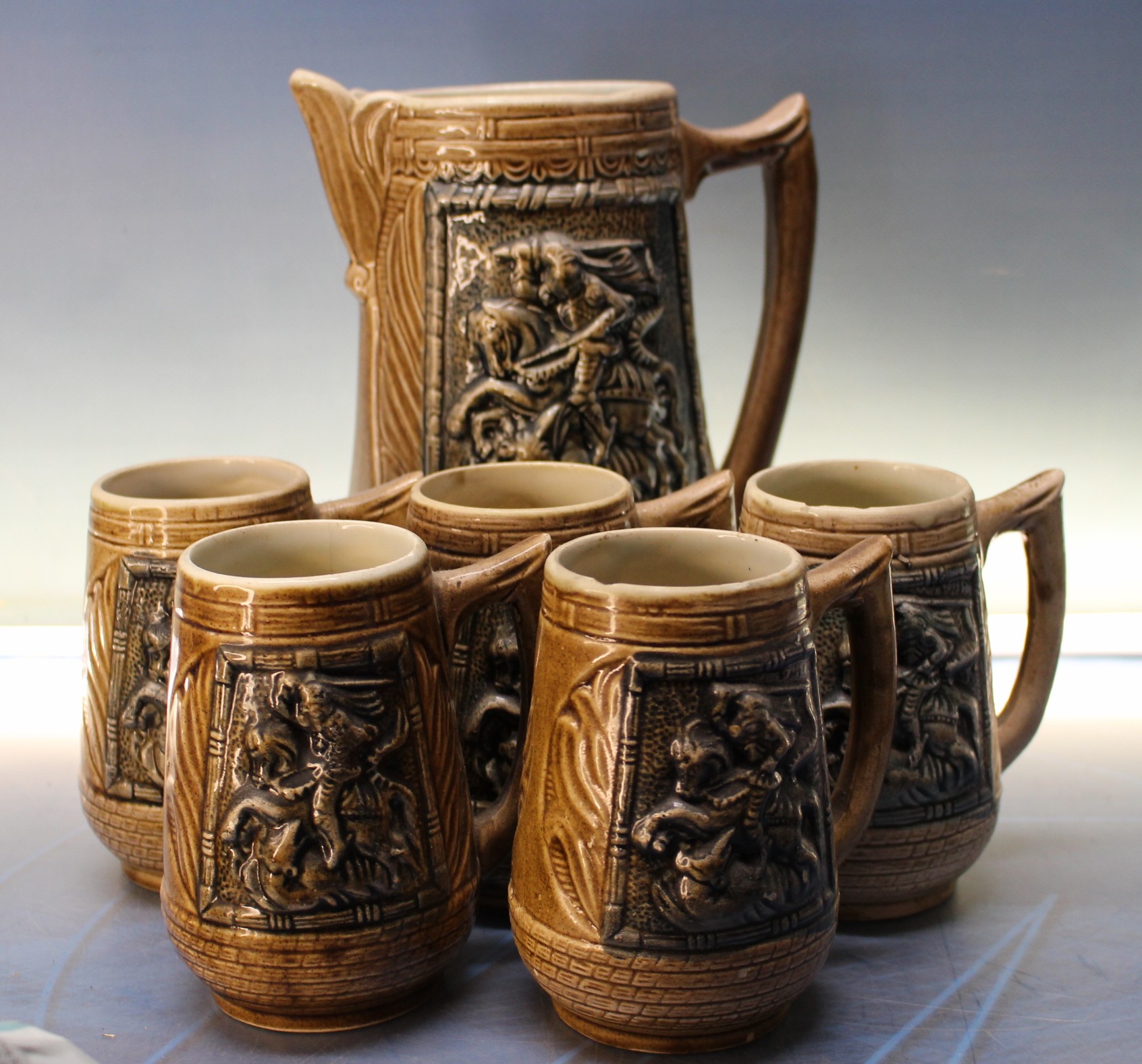 Jarra y jarritas de cerveza. Cerámica con relieve de san Jorge y el dragón.